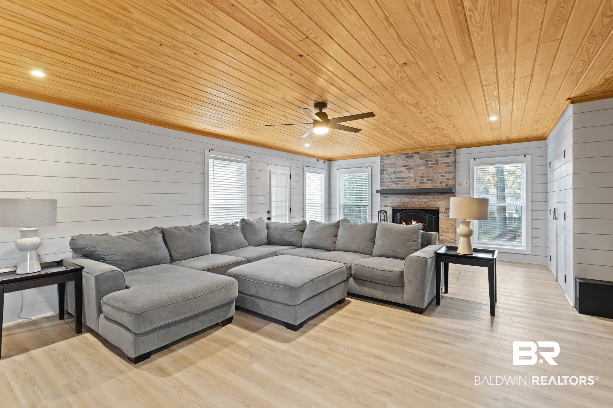 608 Southern Way Daphne, AL 36527 - Photo 13 of 35 Living area with wooden ceiling, wooden walls, a brick fireplace, light wood finished floors, and a ceiling fan