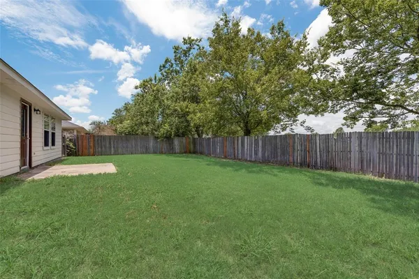 a view of a backyard with a trees and wooden fence