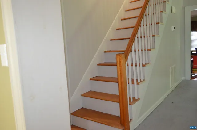 a view of a hallway with wooden floor and stairs