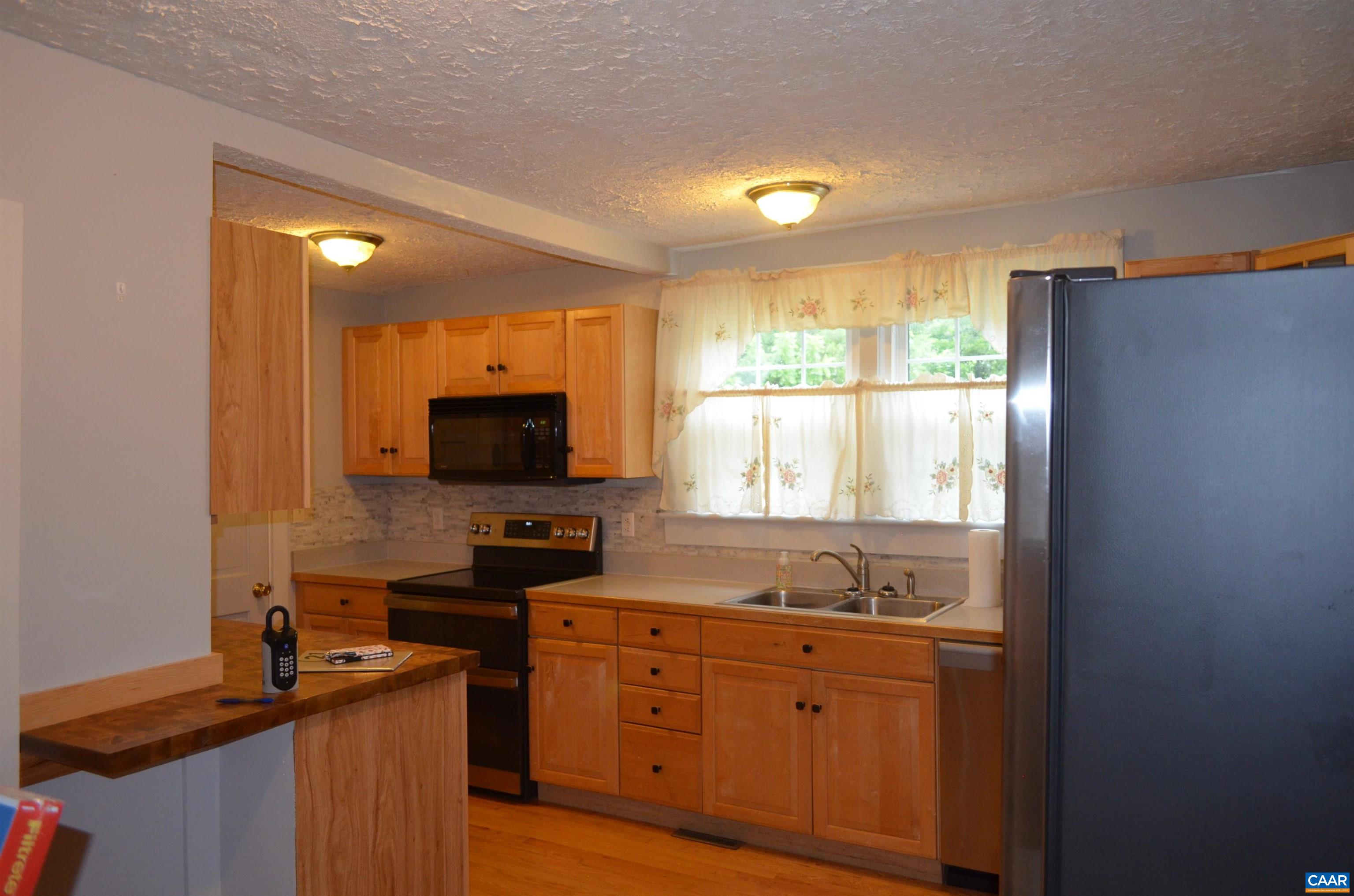10778 Rockfish River Road Shipman, VA 22971 - Photo 23 of 67 a kitchen with granite countertop a refrigerator and a stove top oven