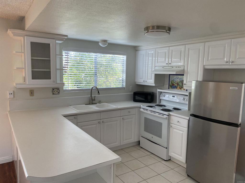 155 Rosebay Drive, Unit 42 Encinitas, CA 92024 - Photo 11 of 13 a kitchen with white cabinets and white appliances