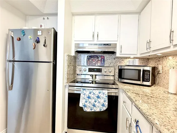 a kitchen with granite countertop white cabinets and white appliances