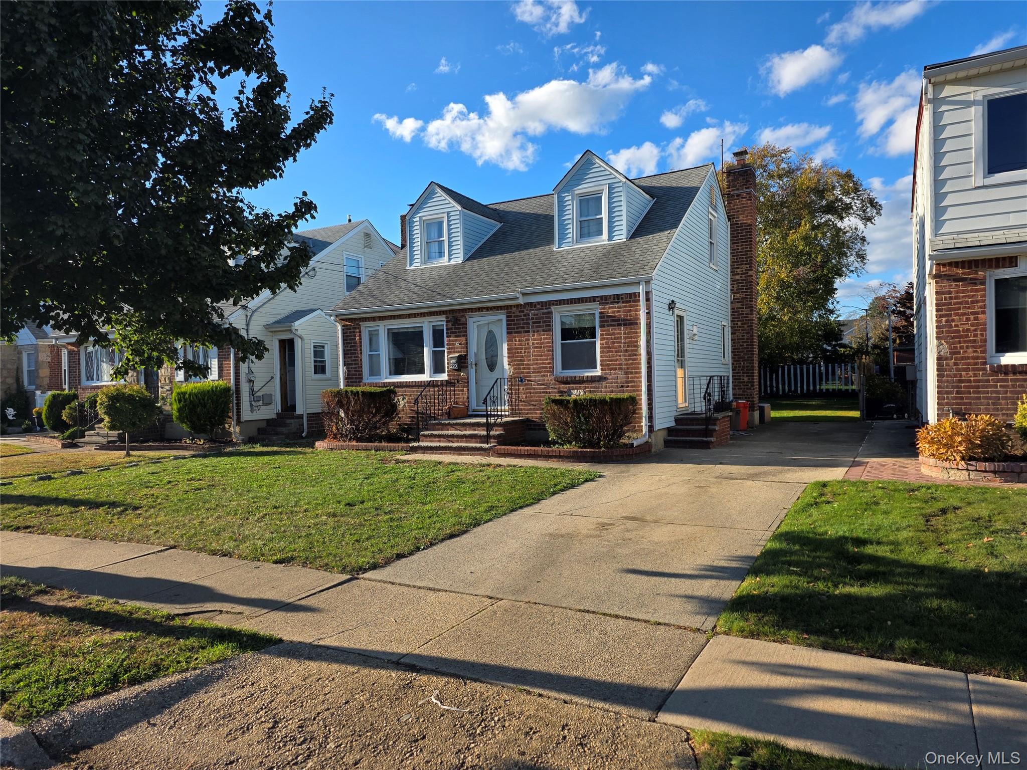 220 Raff Avenue Mineola, NY 11501 - Photo 1 of 22 Cape cod house featuring roof with shingles, a front lawn, brick siding, a chimney, and concrete driveway