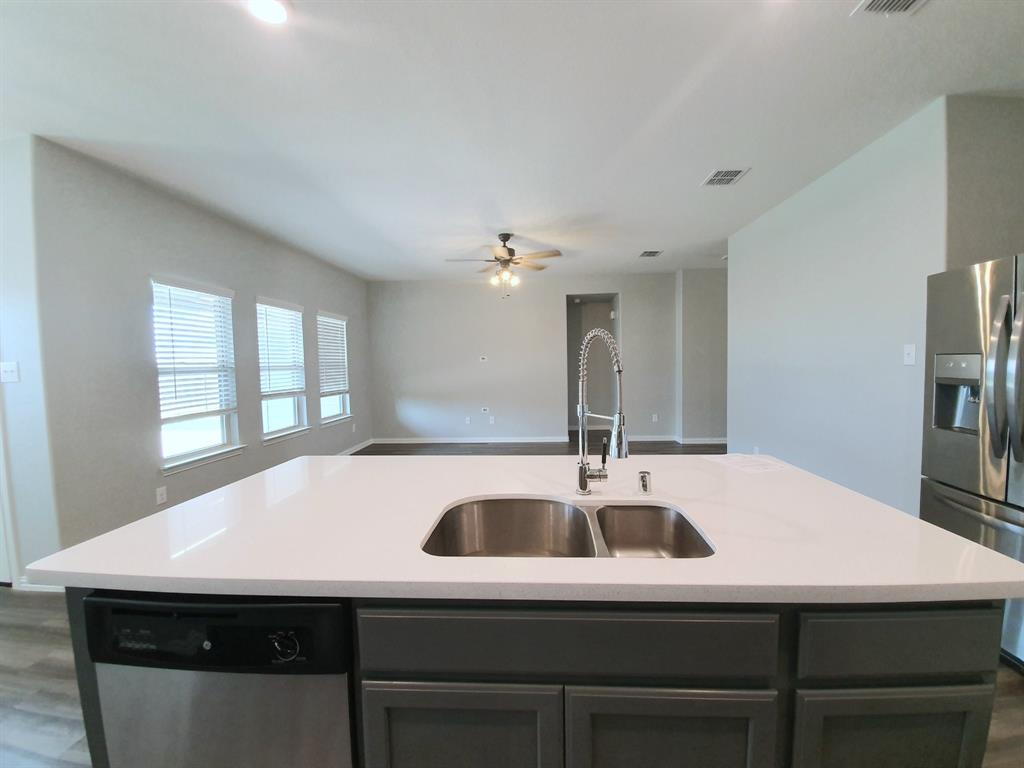 822 Spruce Lane Princeton, TX 75407 - Photo 14 of 35 a kitchen with a table chairs and a refrigerator