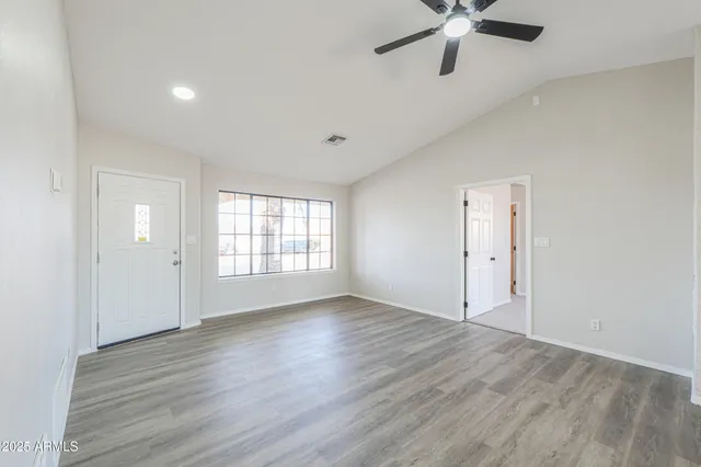 an empty room with wooden floor and windows