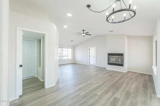 a view of an empty room with wooden floor and window