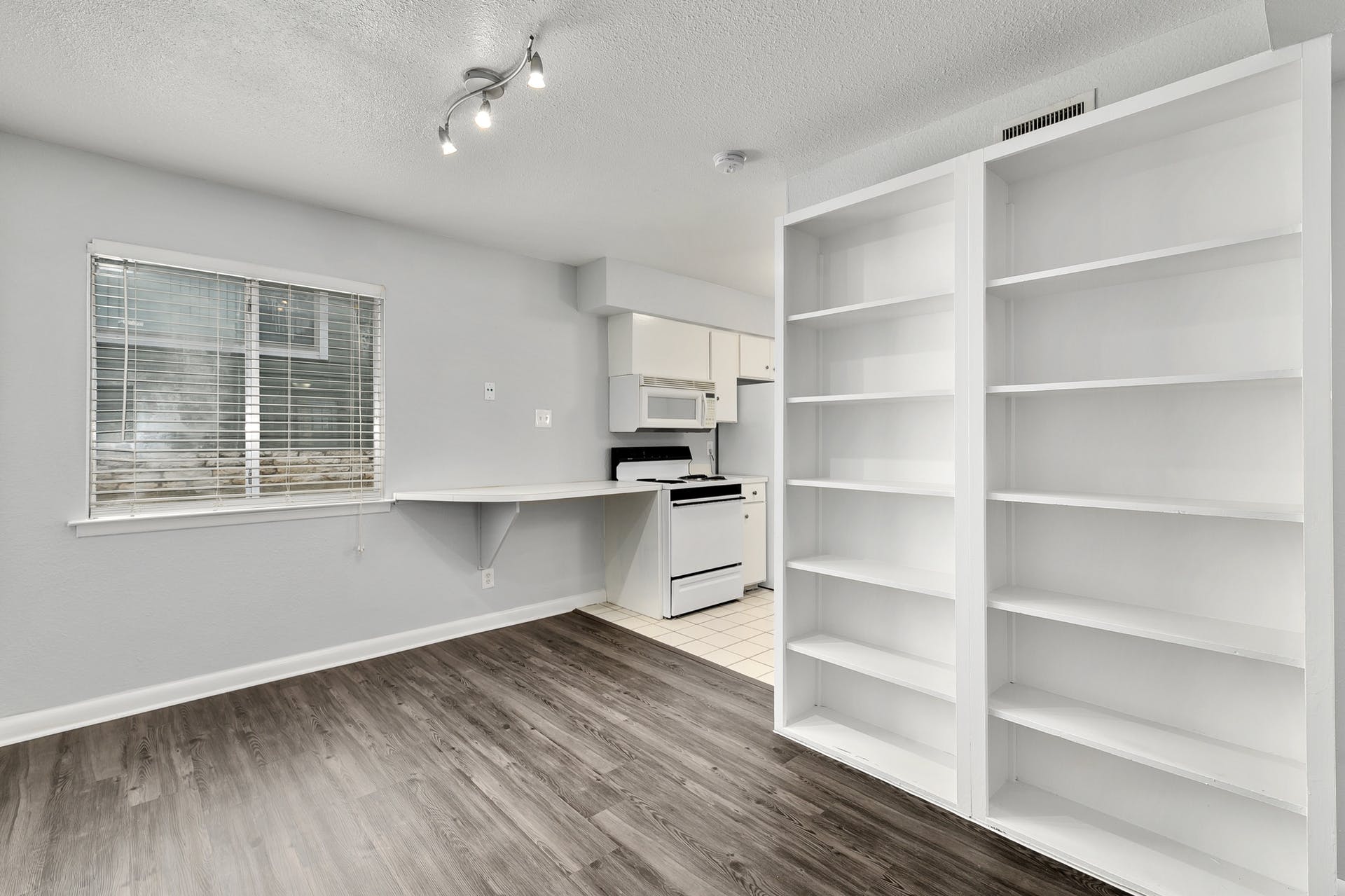 2408 Longview Street, Unit 113 Austin, TX 78705 - Photo 5 of 23 Kitchen featuring white appliances, white cabinets, a textured ceiling, light wood-style flooring, and light countertops