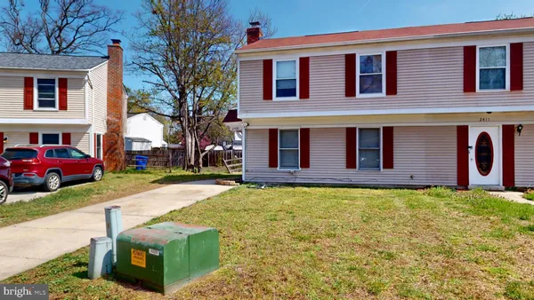 a view of a house with cars park side of a road