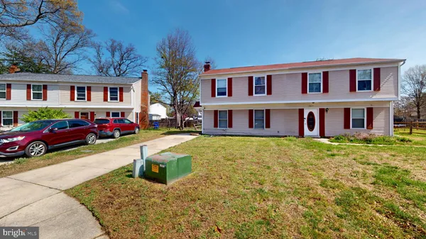a front view of residential houses with yard and trees