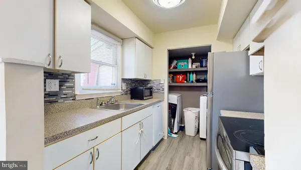 a kitchen with a sink dishwasher a stove and white cabinets with wooden floor