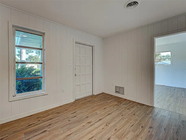 an empty room with wooden floor and windows