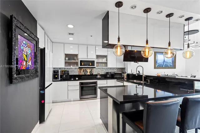 a kitchen with stainless steel appliances kitchen island granite countertop a sink a stove and a microwave