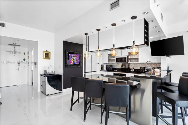 a kitchen with stainless steel appliances granite countertop a stove top oven a refrigerator a stove and a dining table with white cabinets