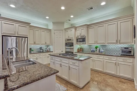 a kitchen with kitchen island granite countertop white cabinets white appliances and granite counter tops