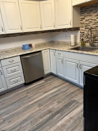 a kitchen with granite countertop a sink cabinets and stainless steel appliances