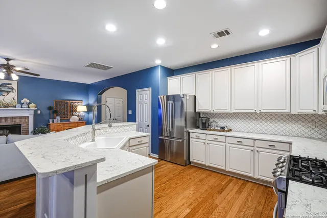 a kitchen with stainless steel appliances kitchen island granite countertop a refrigerator a stove and a sink with wooden floor