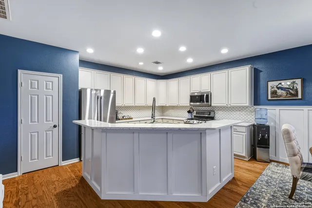 a kitchen with kitchen island a sink stainless steel appliances and cabinets