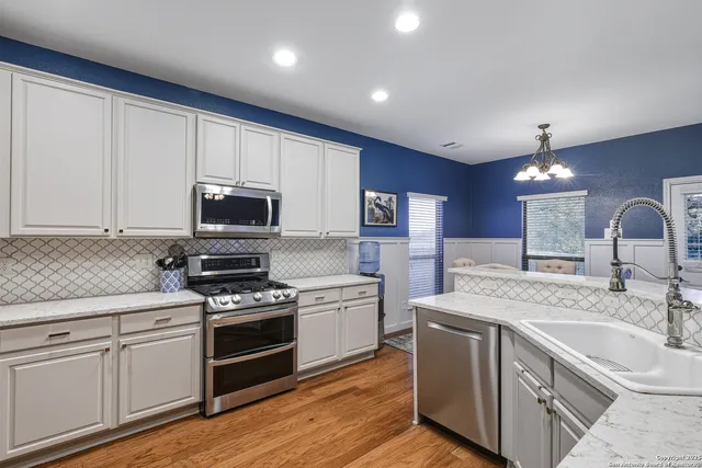 a kitchen with granite countertop a sink stainless steel appliances and cabinets