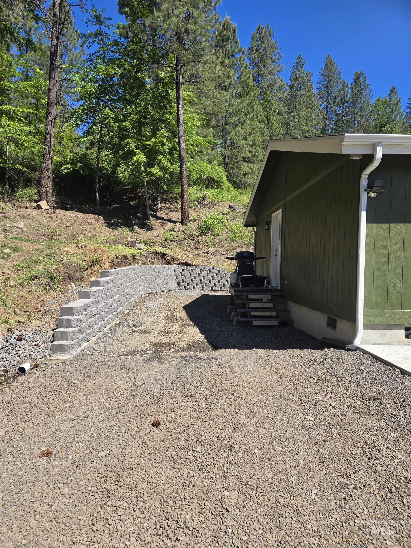 174 Konkolville Road Orofino, ID 83544 - Photo 40 of 43 Gravel driveway with a retaining wall and wood stairs leading to the side entrance