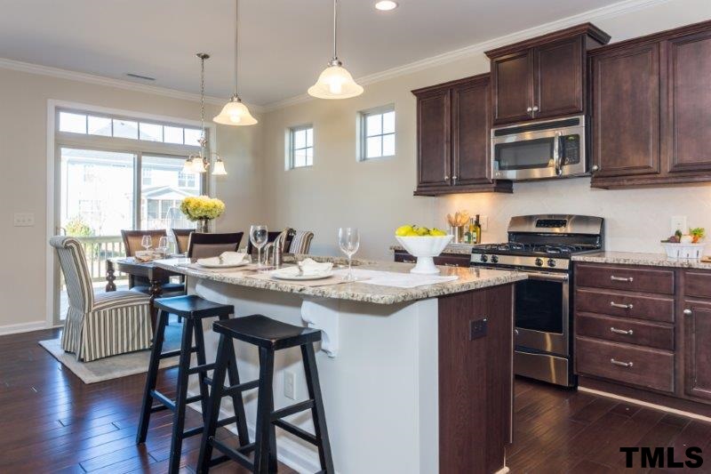 4221 Fares Wall Court Raleigh, NC 27616 - Photo 8 of 25 a kitchen with a sink a stove a dining table and chairs