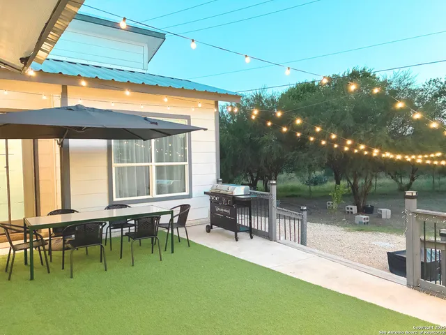 a view of a patio with table and chairs with plants and wooden fence