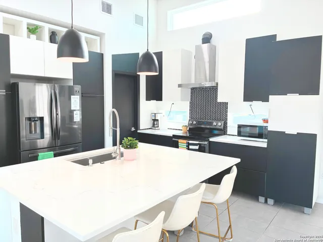 a kitchen with stainless steel appliances kitchen island granite countertop a refrigerator and a stove