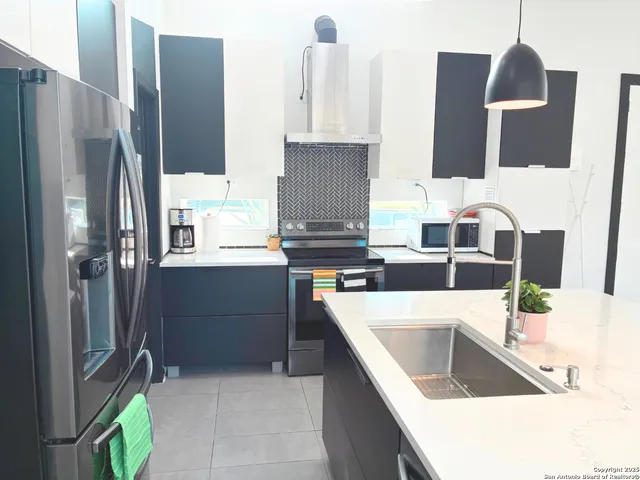 a kitchen with stainless steel appliances granite countertop a sink and a refrigerator