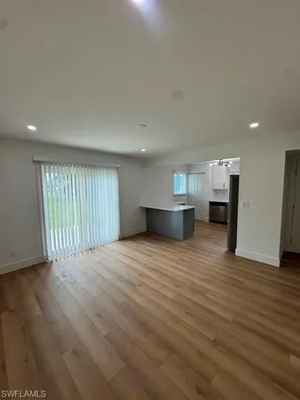 a view of empty room with wooden floor and a window