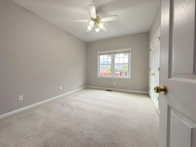 an empty room with windows and ceiling fan