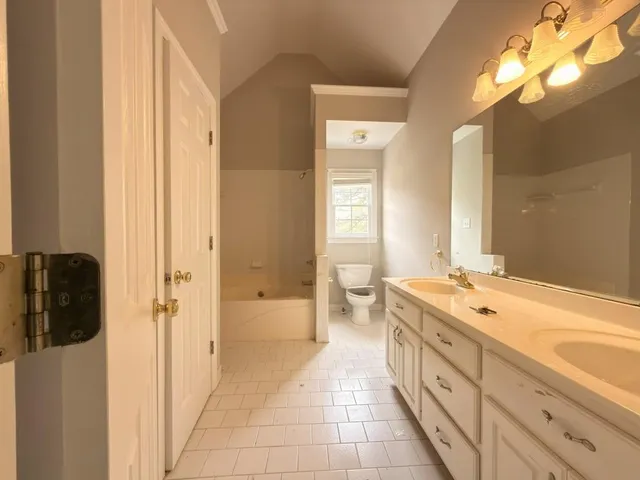 a spacious bathroom with a granite countertop sink a mirror and a bathtub