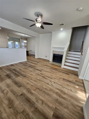 a view of an empty room with wooden floor fireplace and windows