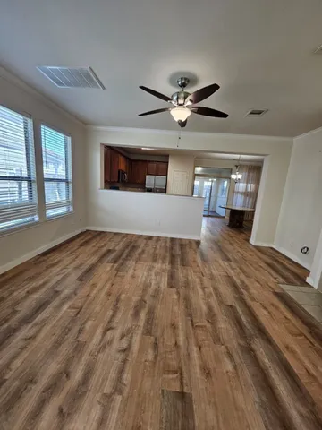 a view of empty room with wooden floor and fan