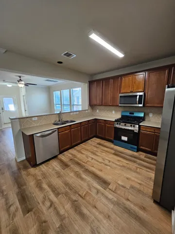 a large kitchen with wooden floors and stainless steel appliances