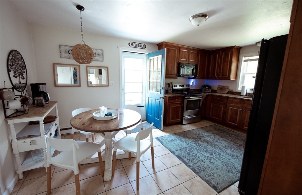 1124 Bemis Road, Unit A Warren, MA 01585 - Photo 13 of 33 a kitchen with stainless steel appliances granite countertop a stove top oven a sink a dining table and chairs with wooden floor