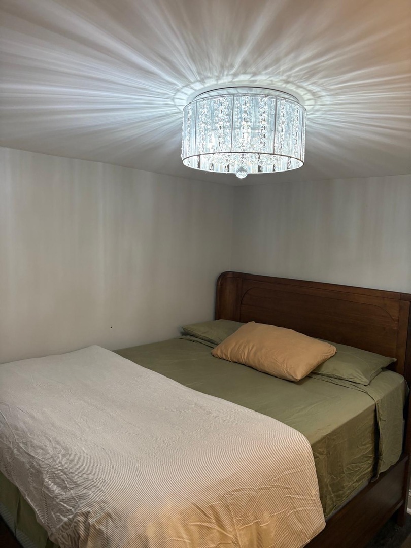 6541 South Ingleside Avenue, Unit G Chicago, IL 60637 - Photo 10 of 13 a bedroom with a bed and chandelier