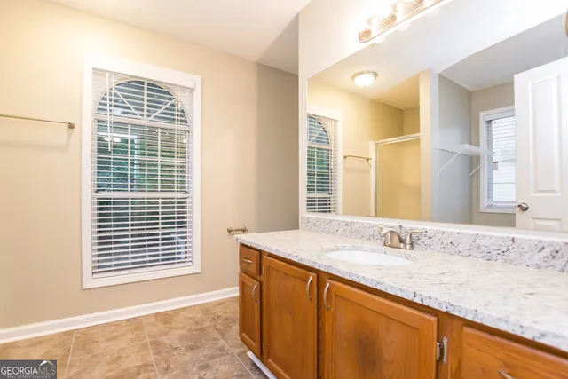 a bathroom with a granite countertop sink and a window