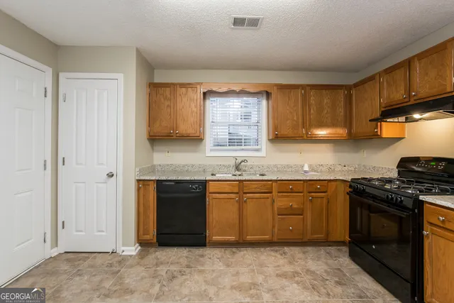 a kitchen with granite countertop stainless steel appliances a stove a sink and a microwave