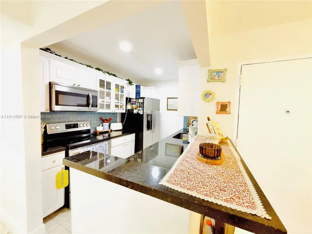 a kitchen with stainless steel appliances granite countertop a sink refrigerator and microwave