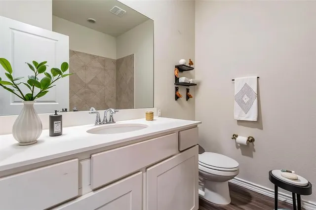 a bathroom with a granite countertop toilet sink and mirror