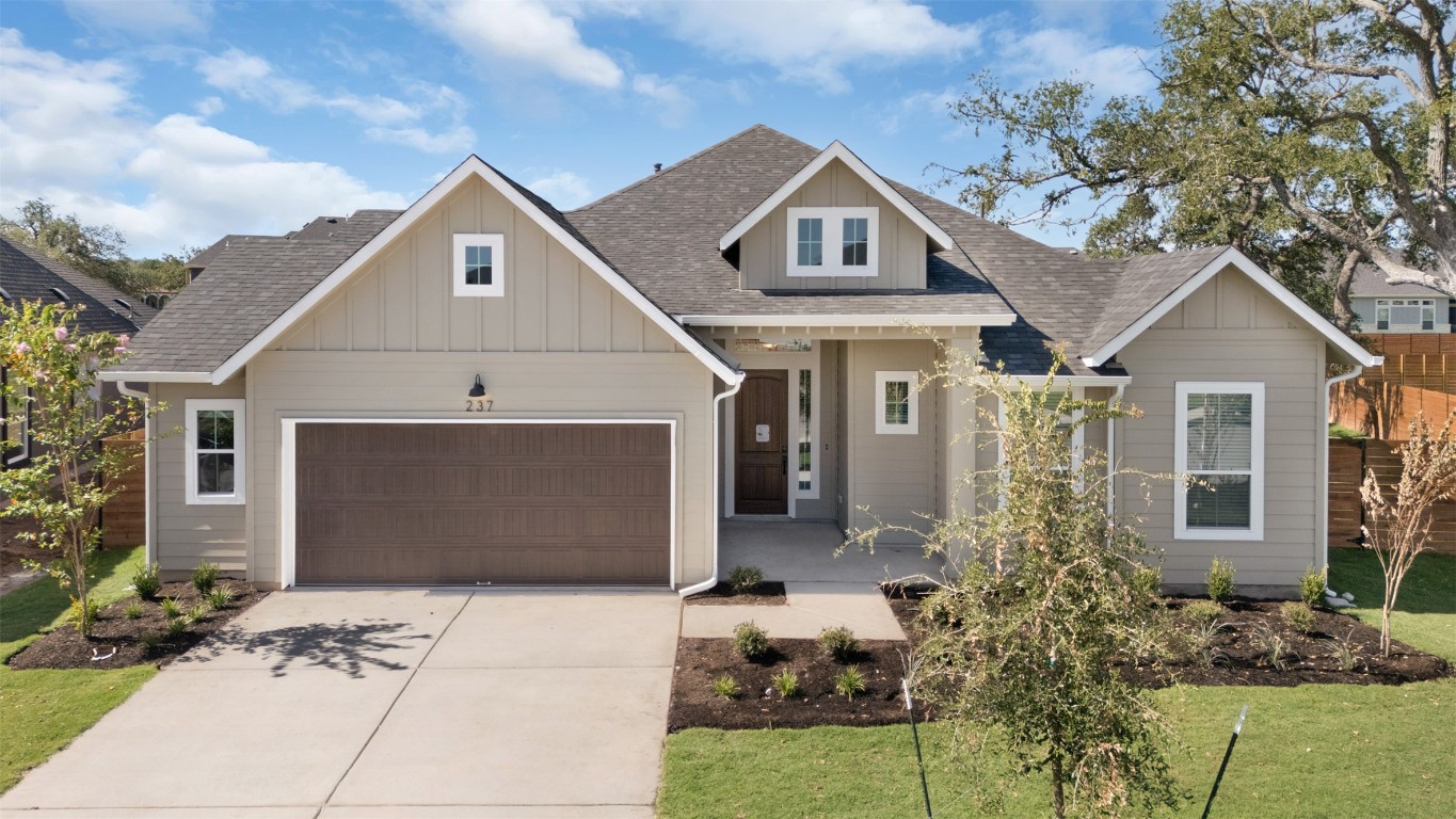 View of front of home with roof with shingles, board and batten siding, driveway, an attached garage, and a front yard