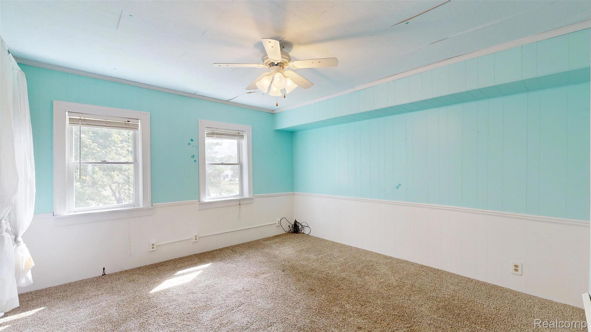 12930 Wilkinson Road Freeland, MI 48623 - Photo 67 of 76 Textured carpeting, two windows with white trim, a ceiling fan with light fixture, and two-tone wall paneling