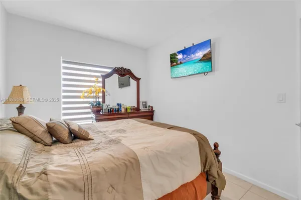 a bedroom with a bed a flat screen tv and a chandelier