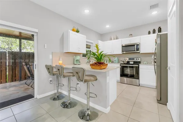 a kitchen with stainless steel appliances kitchen island granite countertop a refrigerator a stove a microwave oven a dining table and chairs with wooden floor