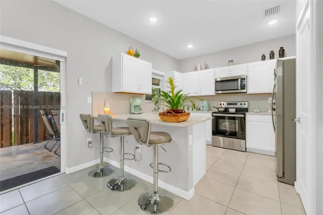 a kitchen with stainless steel appliances kitchen island granite countertop a refrigerator a stove a microwave oven a dining table and chairs with wooden floor