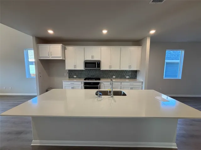 a kitchen with stainless steel appliances granite countertop a stove a sink and white cabinets