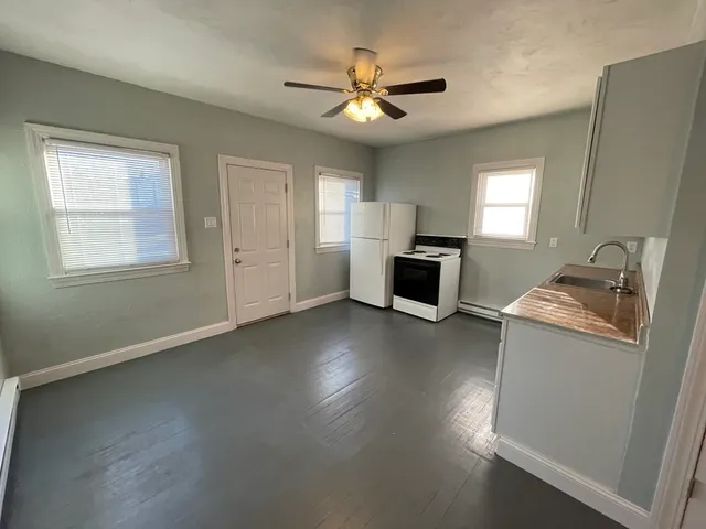 a workspace with wooden floor a ceiling fan and a window