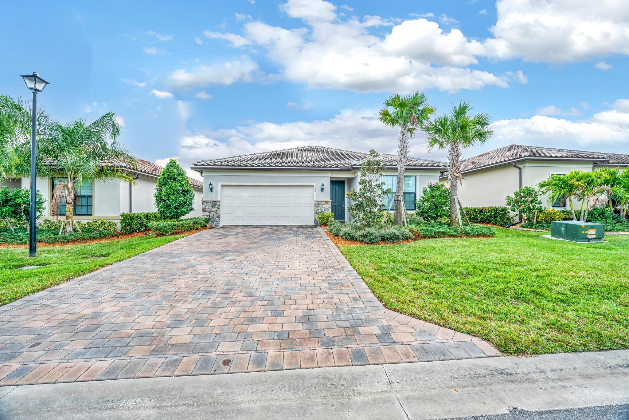 680 Southeast Villandry Way Port St. Lucie, FL 34984 - Photo 1 of 38 a front view of a house with a yard and potted plants