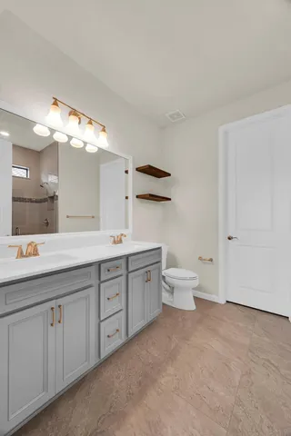 a spacious bathroom with a double vanity sink a toilet and a tub