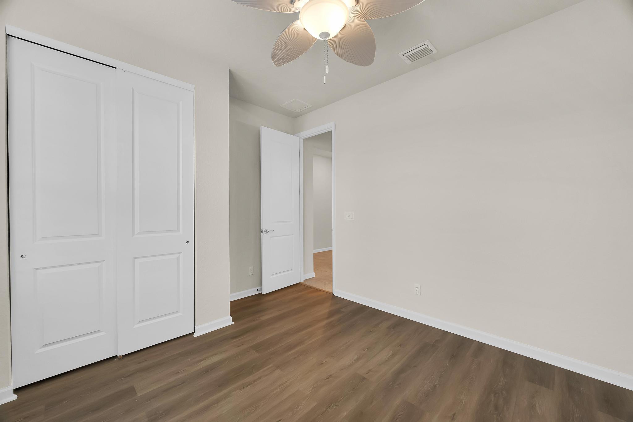 680 Southeast Villandry Way Port St. Lucie, FL 34984 - Photo 17 of 38 a view of an empty room with wooden floor and a ceiling fan
