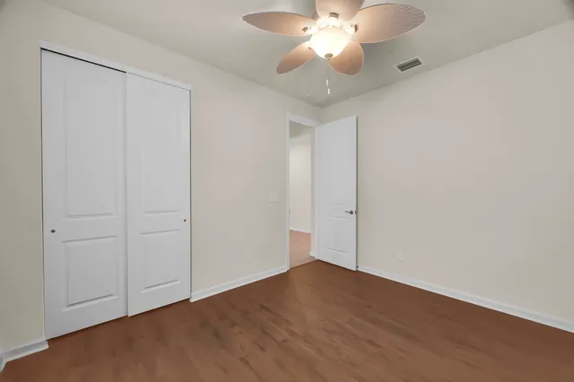 an empty room with wooden floor and fan